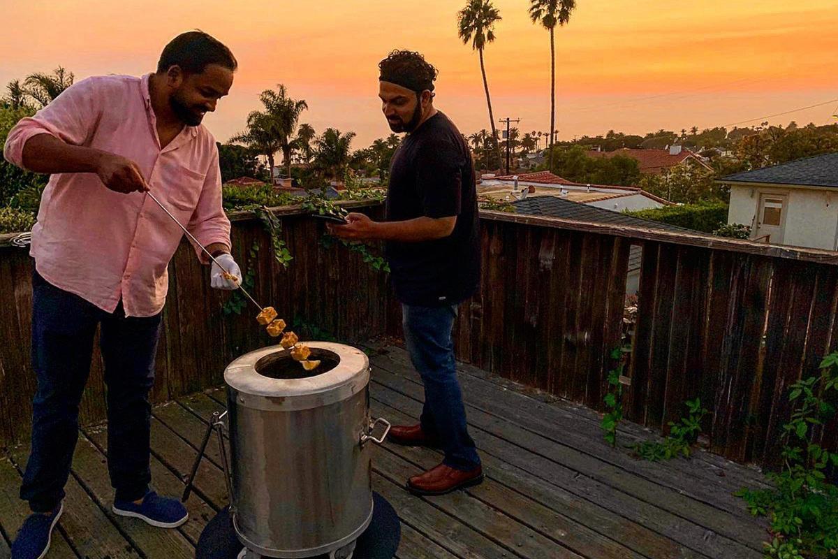 Cooking skewers on a GULATI home tandoor at sunset