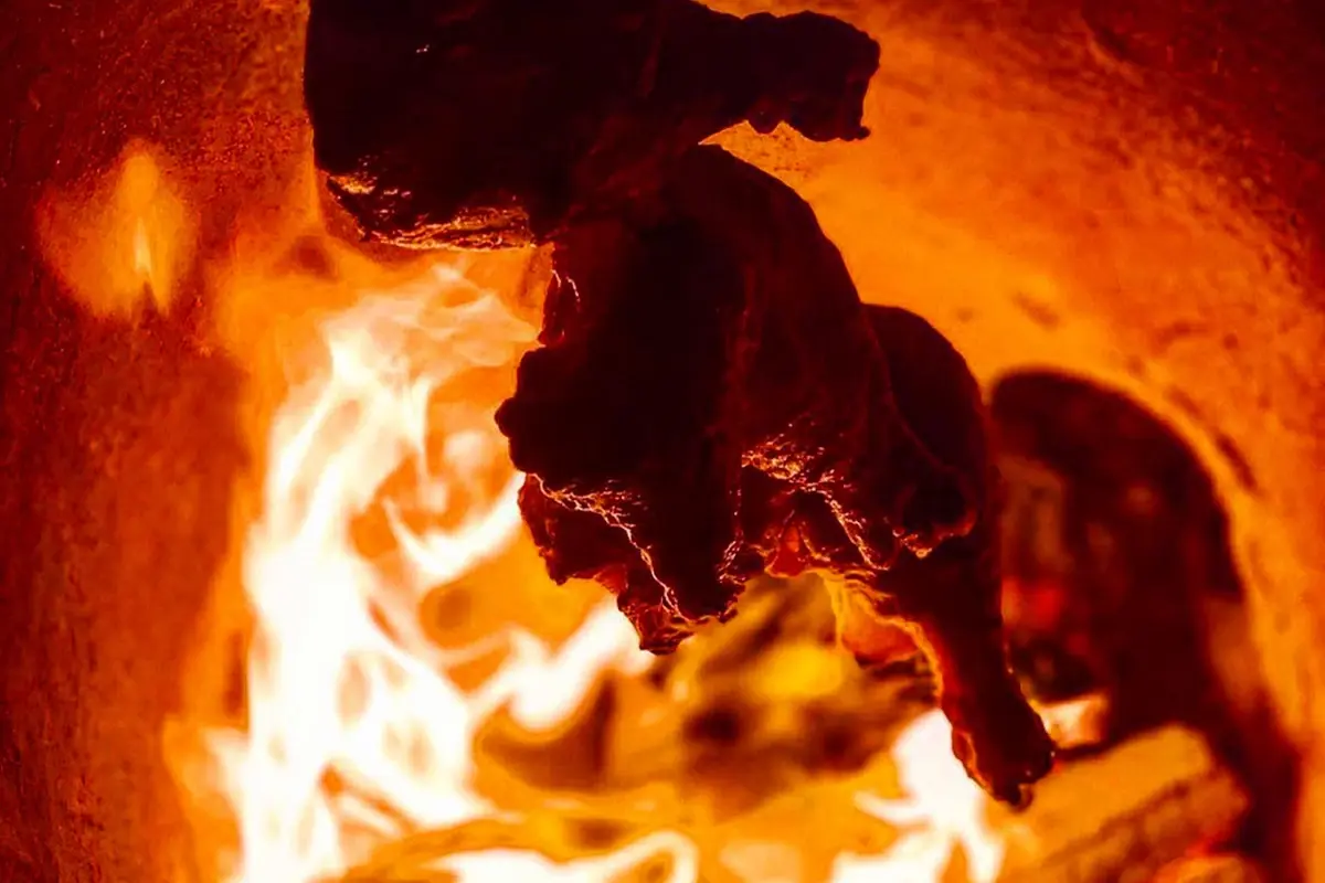 Tandoori chicken roasting over open flame inside a GULATI tandoor